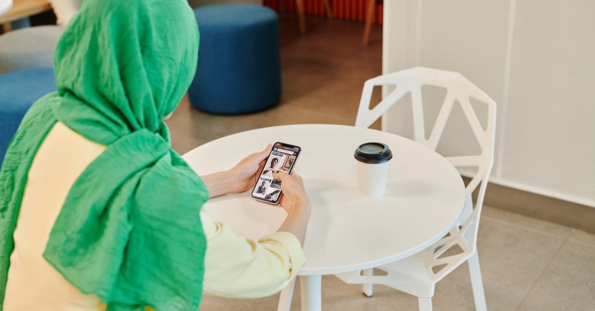 person scrolling phone cafe